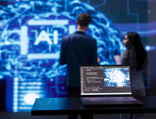 Focus on laptop running AI cognitive computing tech used by IT staff members Focus on laptop running AI cognitive computing tech used by IT staff members in blurry background. Close up of notebook used by teamworking engineers to do data mining with self learning algorithms